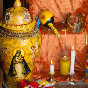 Yellow Urn with La Virgen de Guadalupe on an altar surrounded by Candles.