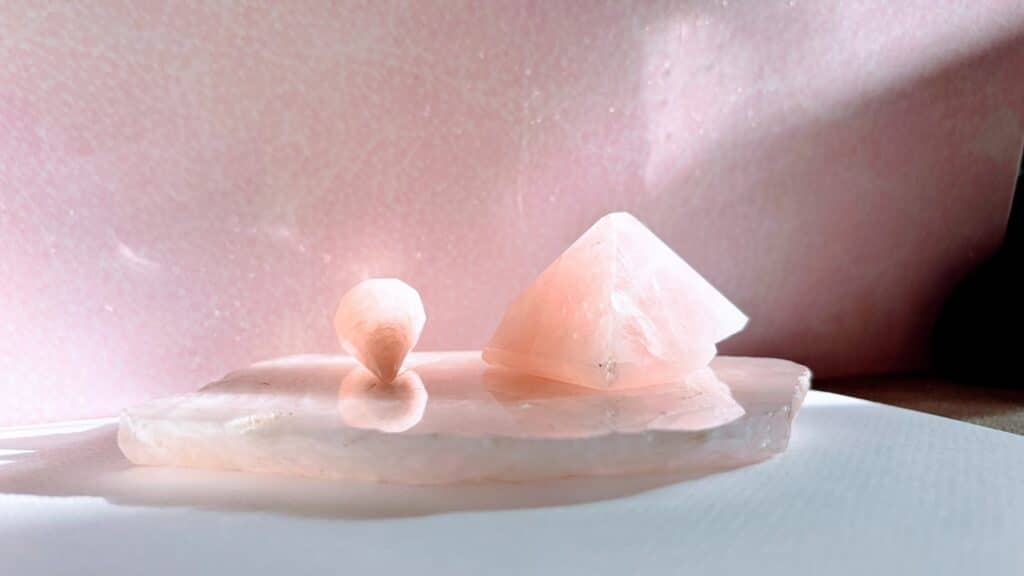 Rose quartz pyramid and pendulum on rose quartz plate